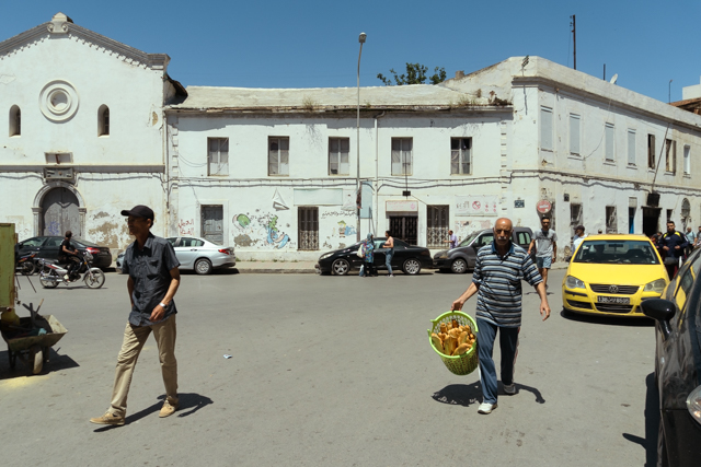 Tunus (Magrib) sokaklarında günlük yaşam, elinde ekmek taşıyan adam, sarı taksi ve tarihi beyaz bina. Belgesel sokak fotoğrafı - Mustafa Tiryakioğlu, Kontrast İstanbul.